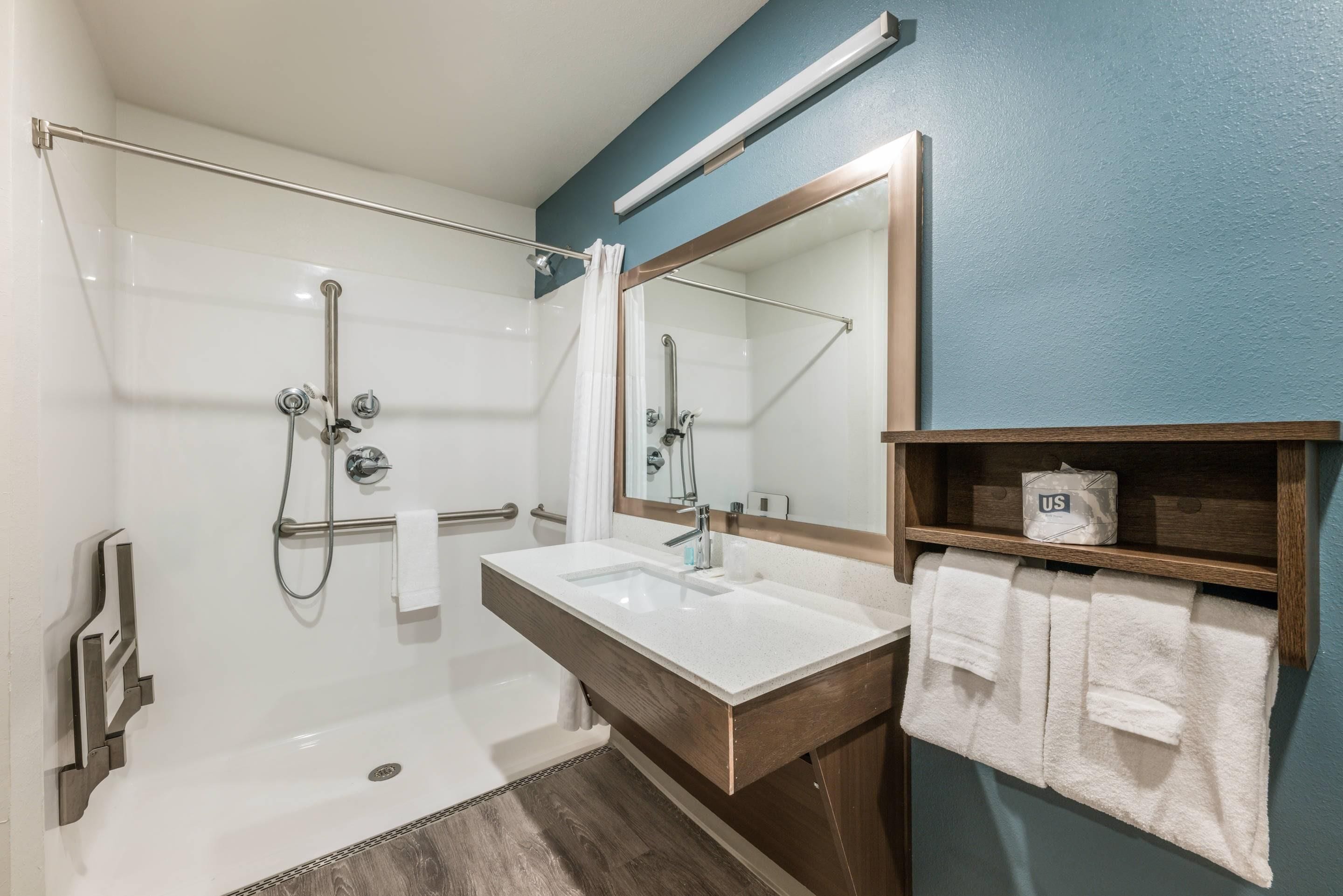 A bathroom with a bathtub, a shower, a sink, and a mirror.