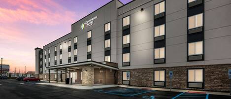 A modern hotel with a flat roof, multiple windows, and a parking lot with handicapped parking spaces.