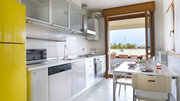 Una cucina moderna completa di lavastoviglie, forno e microonde. È presente un'area pranzo con tavolo e sedie.