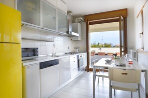 Eine moderne Küche mit Geschirrspüler, Backofen und Mikrowelle. Ein Essbereich mit Tisch und Stühlen ist vorhanden.