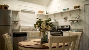 Een keuken met witte kastjes, een eettafel met stoelen, en een vaas met bloemen op de tafel.