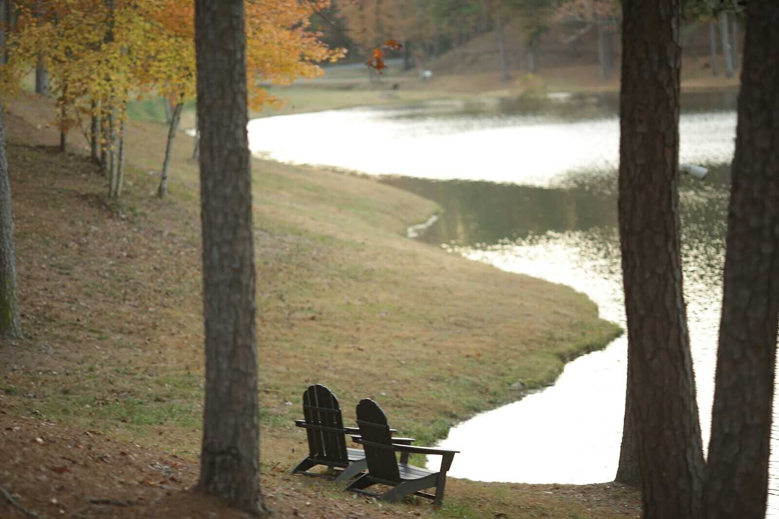A lakeside view with two Adirondack chairs facing the water.