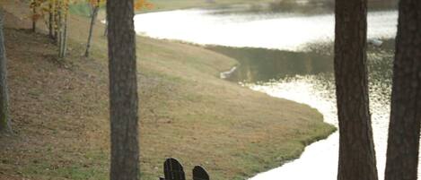 A lakeside view with two Adirondack chairs facing the water.