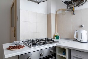 A kitchen with a gas stove, a kettle, and a sink.