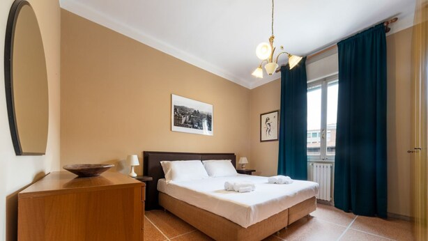 A hotel room with a bed, bedside tables, a dresser, a mirror, and a window with curtains. - UR-NEST Lame, Spacious one bedroom (Bologna)