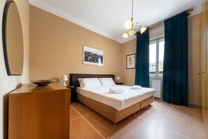 A hotel room with a bed, bedside tables, a dresser, a mirror, and a window with curtains. - UR-NEST Lame, spacious one-bedroom apartment (Bologna)
