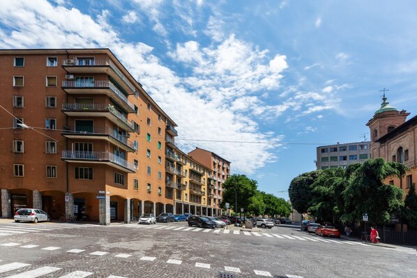 A multi-story building with balconies and a crosswalk in front.