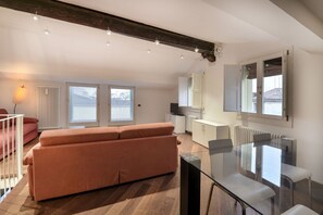 A modern living room with a glass dining table, a sofa, and a staircase leading to an upper floor. - UR-NEST Moline, Lovely three bedroom two bathroom apartment (Bologna)
