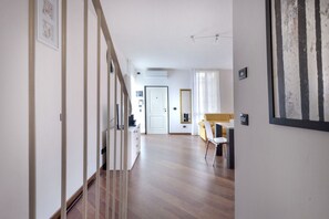 A hallway with wooden flooring, a staircase, a dining area with a yellow chair, and a white door. - UR-NEST Moline, Stunning Apartment (Bologna)