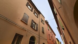 Una calle estrecha con edificios que presentan puertas y ventanas de arco con contraventanas.