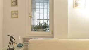 Un dormitorio con cama, una mesita de noche con una vela y una ventana con persianas.