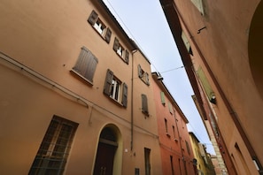 A narrow street with buildings featuring arched doorways and windows with shutters.