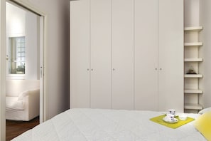 A bedroom with a bed, a wardrobe, a chair, and a window.