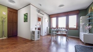 A spacious living area with wooden flooring, a dining table with chairs, a sofa, and a large window providing natural light. - UR-NEST Saffi, Silent and very sunny 90 sqm (Bologna)