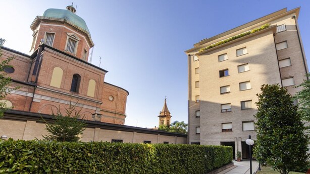 A building with a brick facade and a dome, adjacent to a modern apartment building. - UR-NEST Saffi, Silent and very sunny 90 sqm (Bologna)