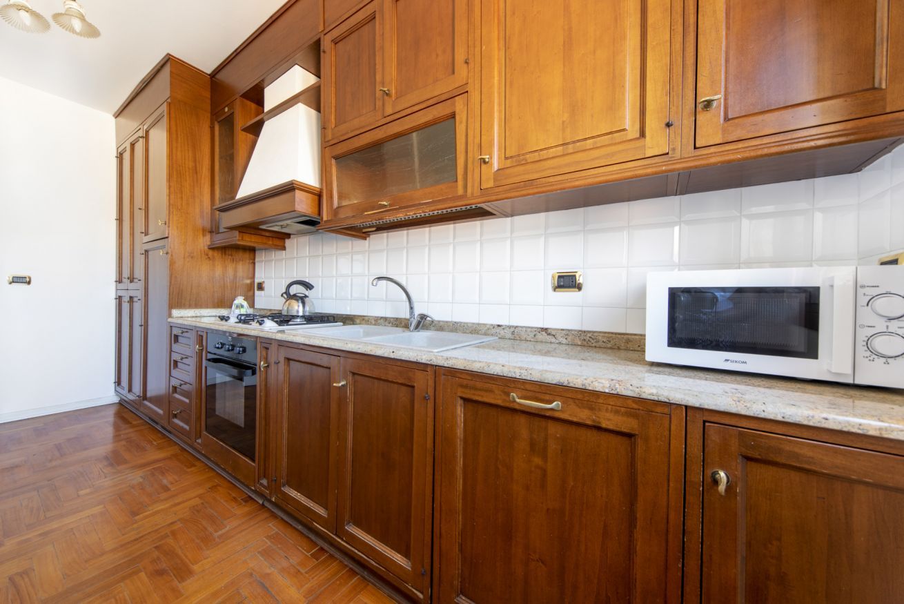 A kitchen with wooden cabinets, a microwave, a stove, and a sink.
