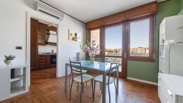 Una cucina compatta con mobili in legno, un tavolo da pranzo con sedie e un'ampia finestra con vista sulla città.