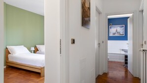 A room with a bed, a nightstand, a wall-mounted light, and a door leading to another room. - UR-NEST Saffi, Silent and very sunny 90 sqm (Bologna)