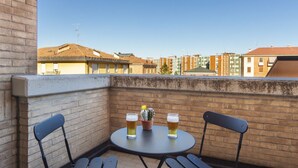 A balcony with two chairs and a small table, two glasses of beer, and a cactus plant. - UR-NEST Saffi, Silent and very sunny 90 sqm (Bologna)