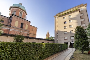 A building with a brick facade and a dome, adjacent to a modern apartment building.