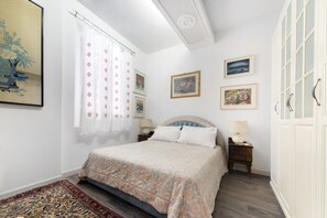 A bedroom with a bed, a nightstand, a lamp, and a window with curtains.