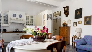 Un coin repas comprenant une table ronde, des chaises, un vase de fleurs et un buffet contenant de la vaisselle.