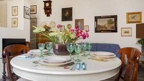 Une table à manger dressée avec des assiettes, des verres et un vase de fleurs.