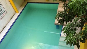 Ein rechteckiger, überdachter Pool mit blauer Umrandung und gefliestem Boden.