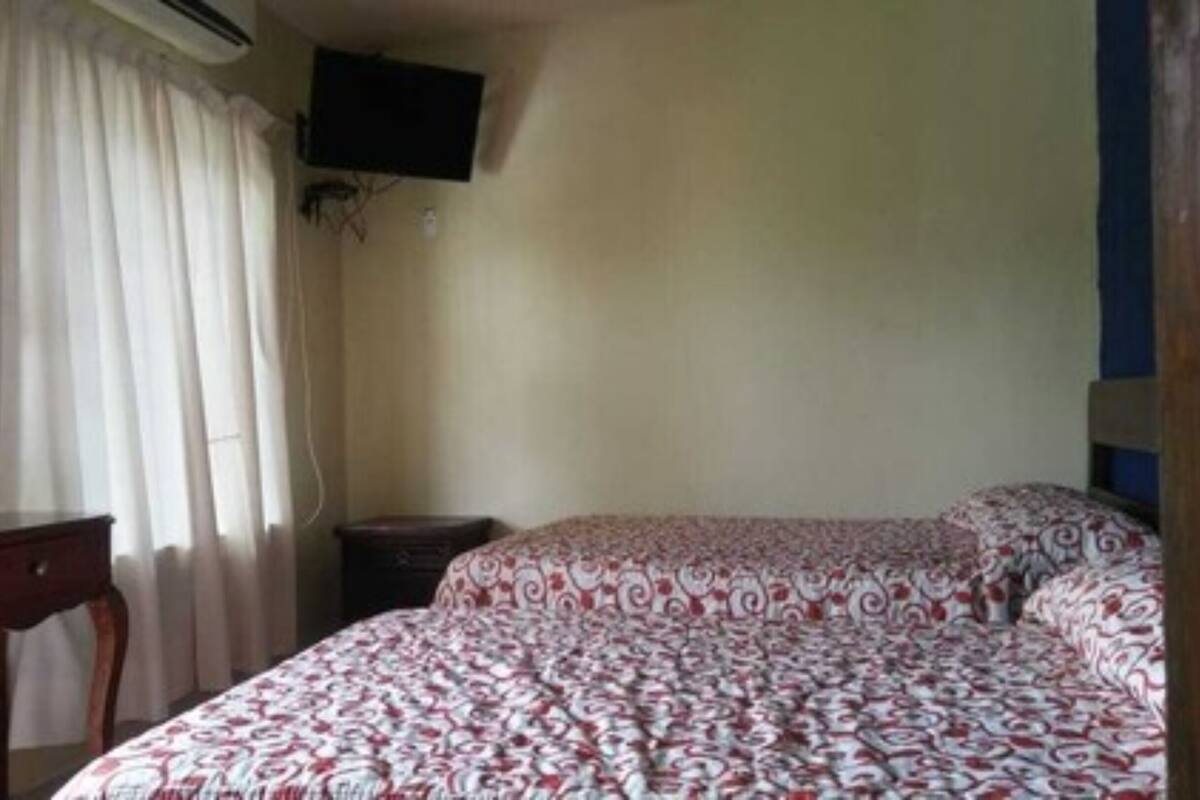 A room with a bed, a desk, and a TV mounted on the wall.