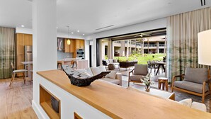 Une cuisine moderne avec des meubles en bois, un coin repas comprenant une table et des chaises en bois, et une grande fenêtre donnant sur un jardin.