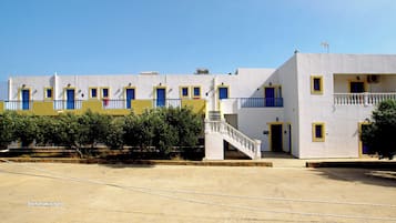 Un edificio bianco con porte e finestre blu, un balcone e una scala che conduce a un piano superiore.