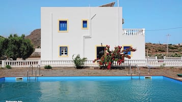 Un edificio bianco con decorazioni blu e una piscina di fronte.
