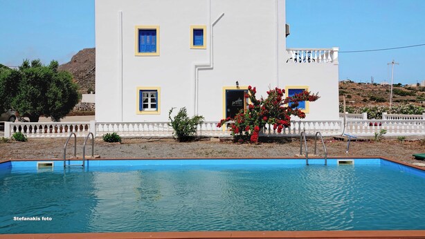 Un edificio blanco con detalles azules y una piscina delantera.
