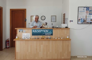 A reception desk with a sign reading "RECEPTION AERIKO" and a clock on the wall.