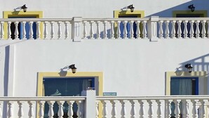 Un hotel con varios balcones, cada uno con barandilla blanca y un ventanal pequeño.