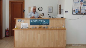 Un mostrador de recepción con un letrero que dice "RECEPTION AERIKO" y un reloj en la pared.