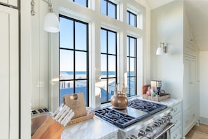 A kitchen with a large window, a gas stove, and a coffee maker. - Blue View | Stunning Home with Gulf Views | Seaside, FL | 4BR/4.5BTH (Santa Rosa Beach)