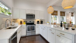 A modern kitchen with white cabinetry, stainless steel appliances, and a wooden floor. - Luxury@Dwell /Rooftop With Views/ Mins to Downtown (Nashville)