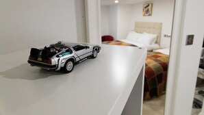 A hotel room with a bed, a nightstand, and a toy car on the nightstand. - Westwood Apartment (Leeds)