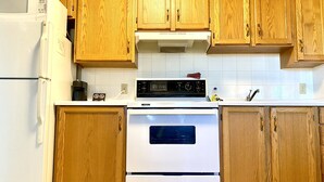 Una cocina con armarios de madera, un refrigerador blanco, una estufa y un microondas.
