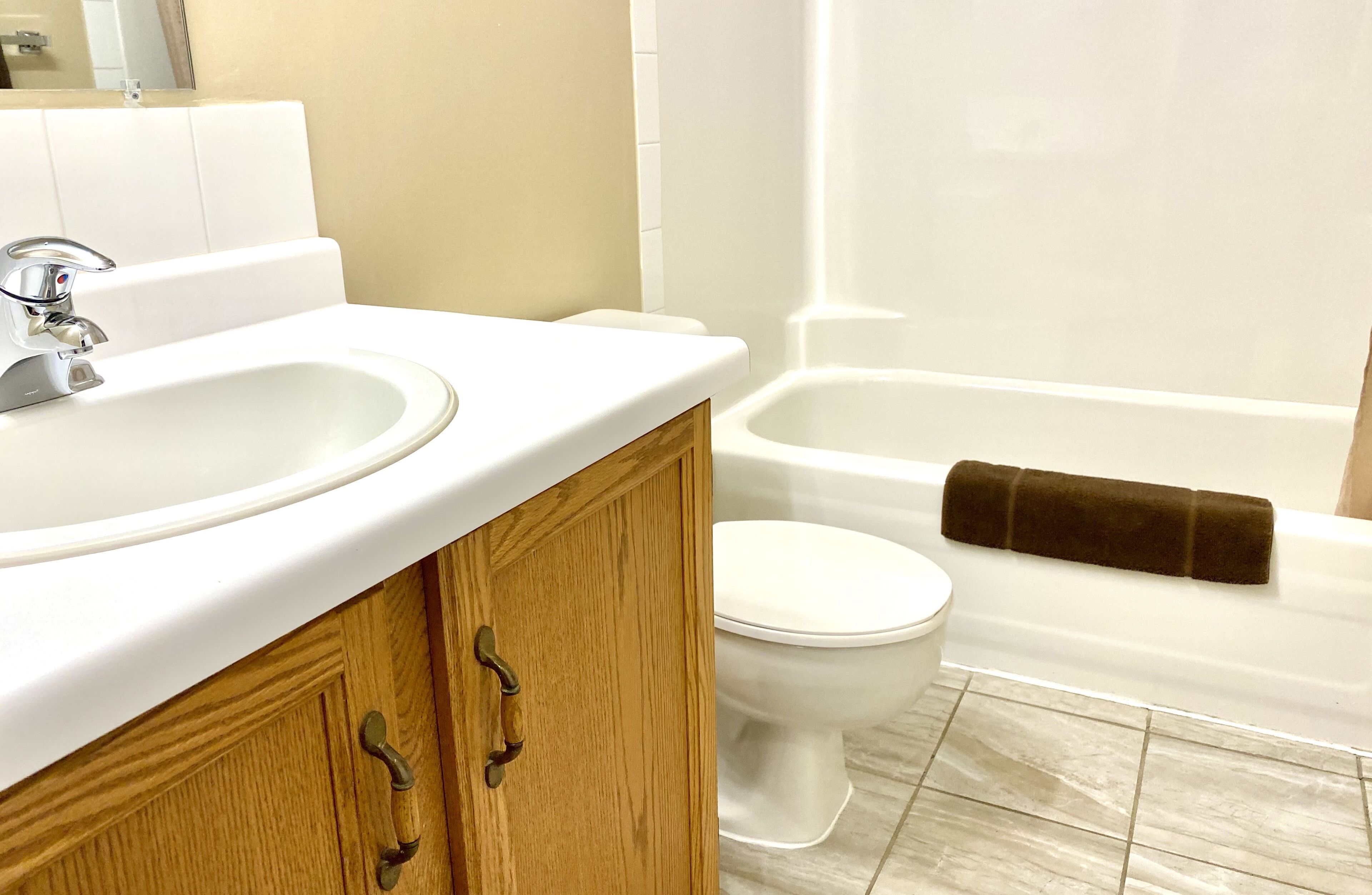 Un baño con lavamanos blanco, mueble de madera, inodoro y bañera.