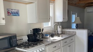 Une cuisine avec des meubles blancs, une cuisinière, un four à micro-ondes et un évier.