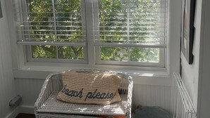 Une pièce dotée d’une grande baie vitrée, d’un panier en osier avec un coussin et d’un panier pour animaux de compagnie.