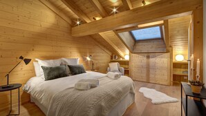 A cozy wooden room with a bed, bedside lamps, a chair, and a skylight. - Dorealp - superb apartment for 6 in peaceful setting - OVO Network (La Clusaz)