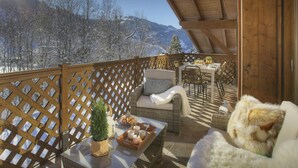 A wooden deck with wicker furniture, a small table with a tray of croissants, and a potted plant. - Dorealp - superb apartment for 6 in peaceful setting - OVO Network (La Clusaz)