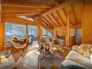 A cozy cabin interior with a wooden ceiling, a dining area, and a view of the snowy outdoors. - Dorealp - superb apartment for 6 in peaceful setting - OVO Network (La Clusaz)