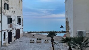 Una calle estrecha flanqueada por edificios, una pequeña piscina y vistas al mar.