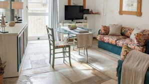 Una sala de estar con sofá, televisor, mesa de vidrio y balcón.