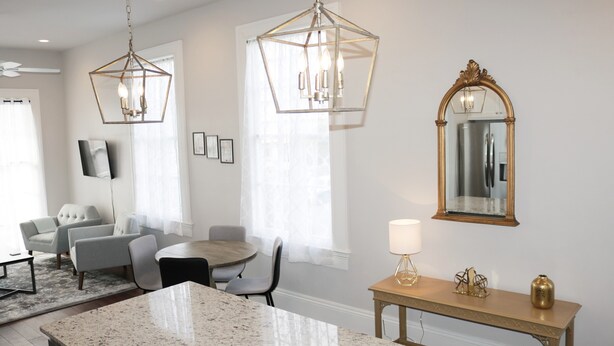 Una cocina moderna con encimeras de granito, un comedor con mesa redonda e iluminación colgante.
