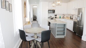 Una cocina moderna con gabinetes blancos, electrodomésticos de acero inoxidable y una isla central con sillas.